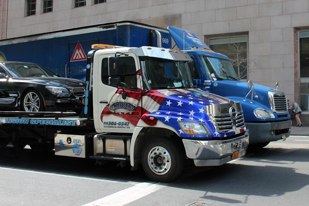 A picture of a tow truck transporting a vehicle that is covered with Red Shield Administration